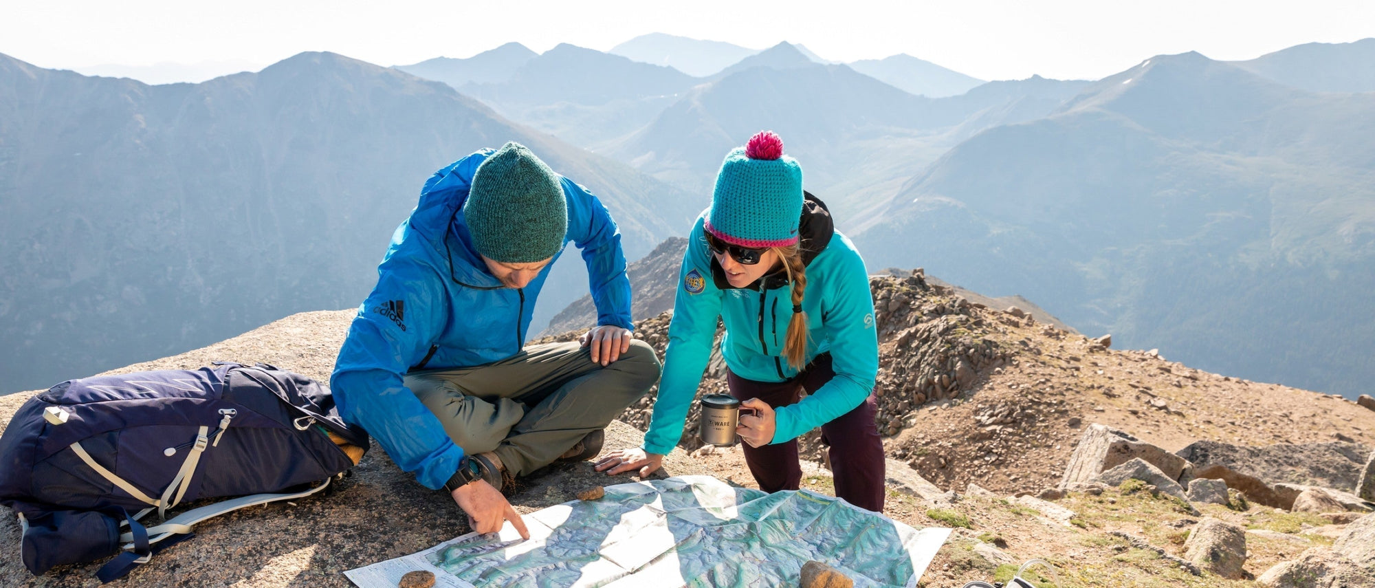Male and female hiker taking a break in the mountains as they study the map together.